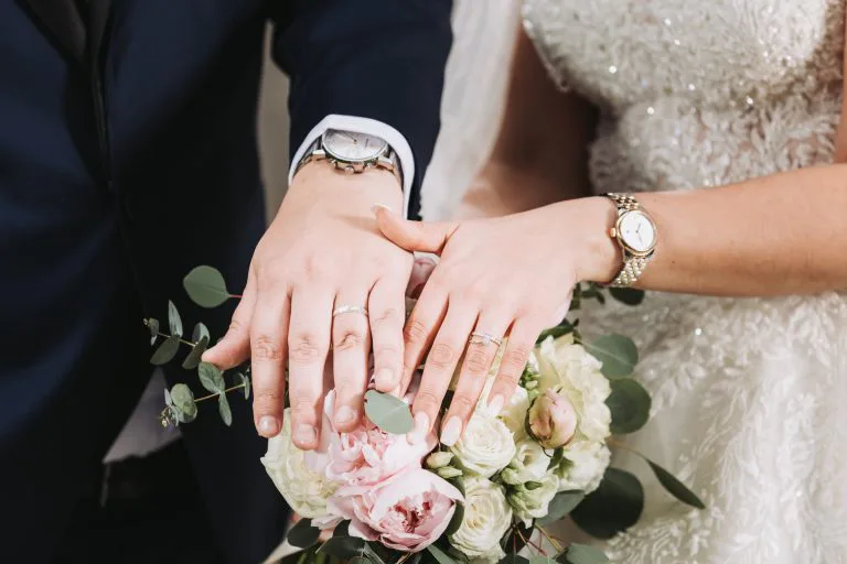 Les mains des mariés et leurs alliances posées sur le bouquet — photographe de mariage à Lyon