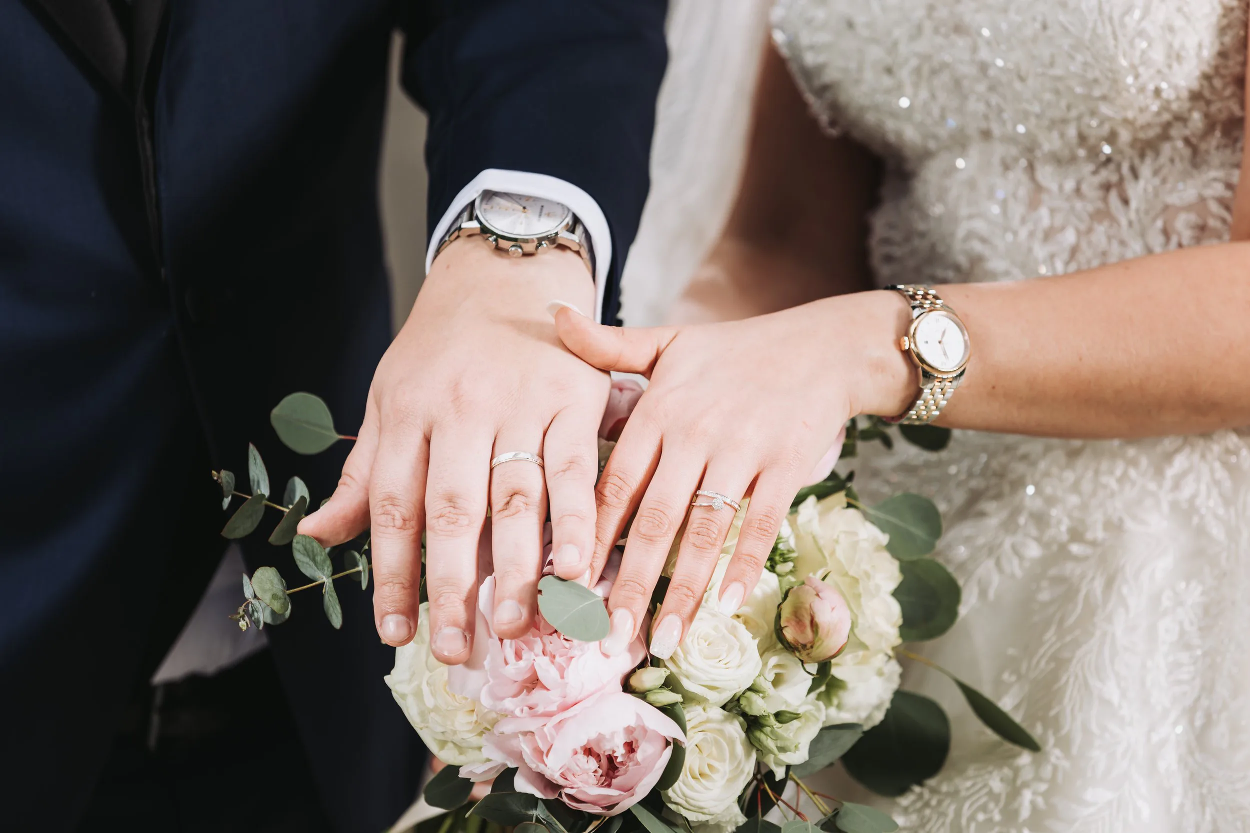 Les mains des mariés et leurs alliances posées sur le bouquet — photographe de mariage à Lyon