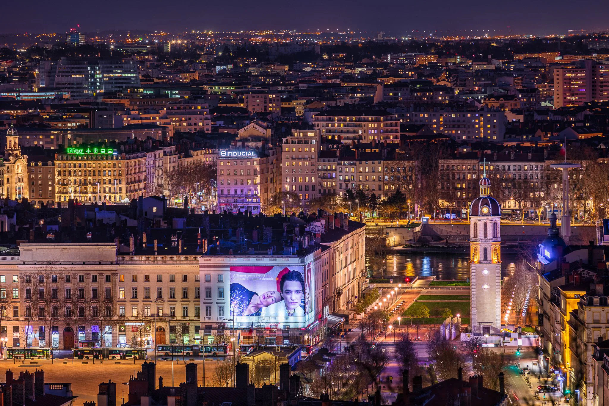 Lyon de nuit et une bâche publicitaire illuminée sur une façade