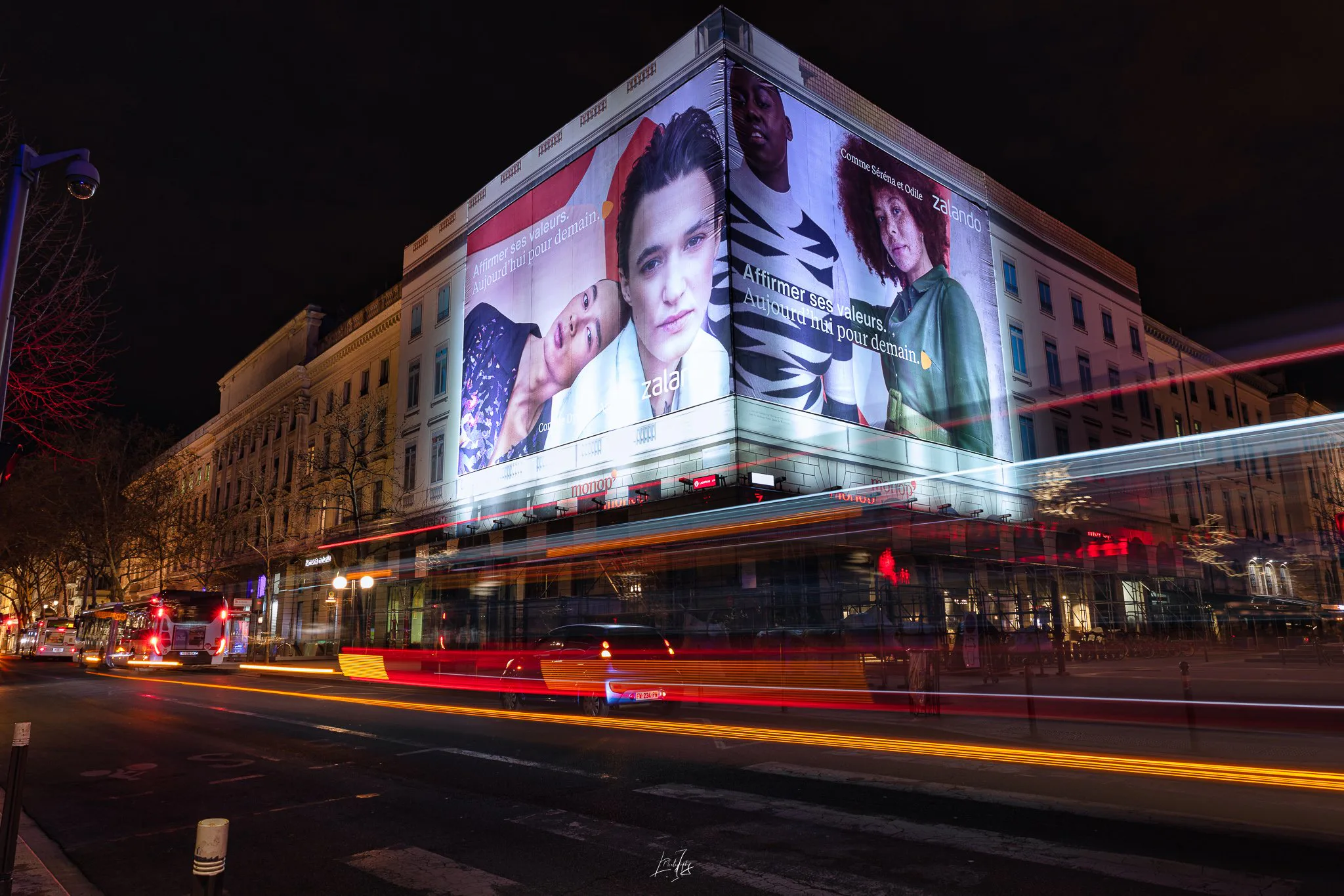 Bâche publicitaire illuminée sur une façade de Lyon, la nuit