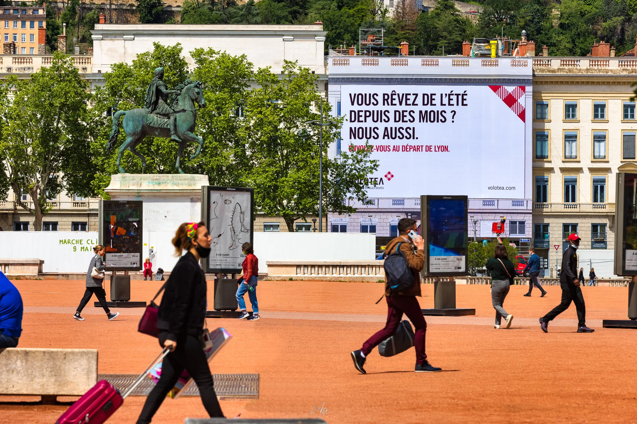 Place Bellecour animée devant la bâche Volotea et la statue de Louis XIV