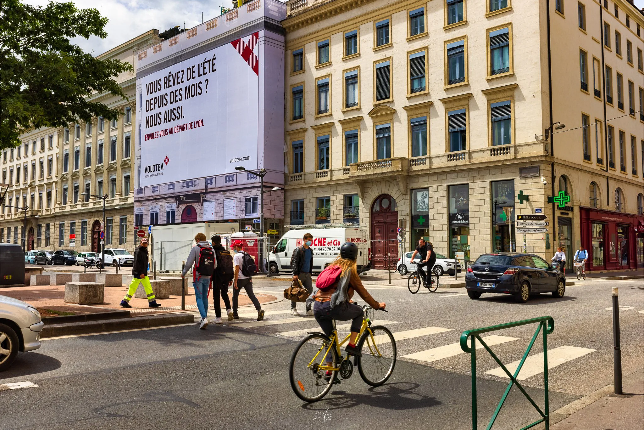 Cycliste et bâche publicitaire Volotea sur une façade de la place Bellecour