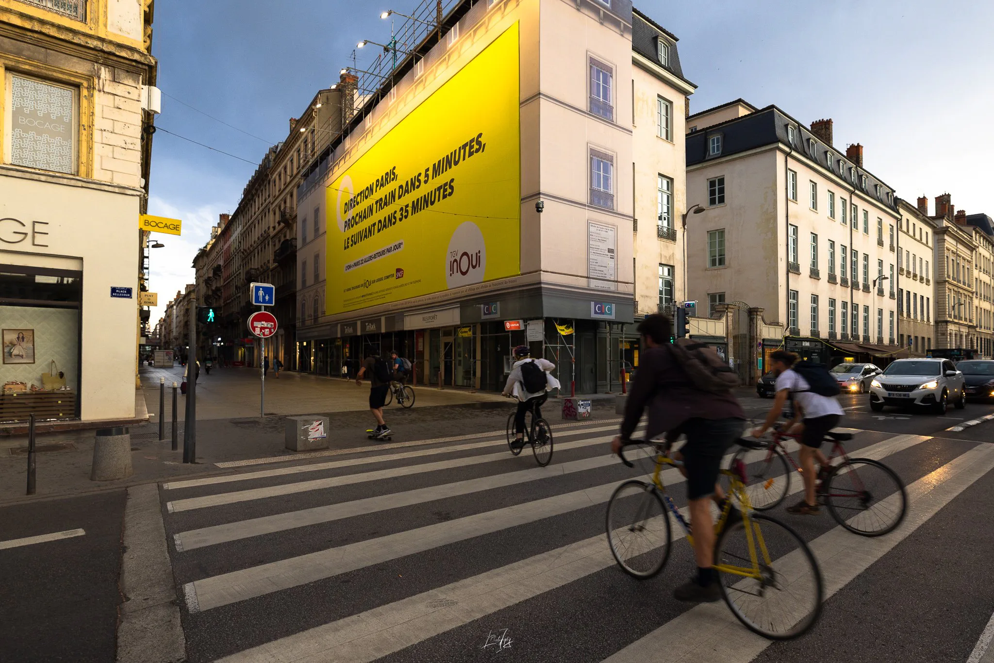 Bâche publicitaire SNCF et cyclistes dans une rue de Lyon