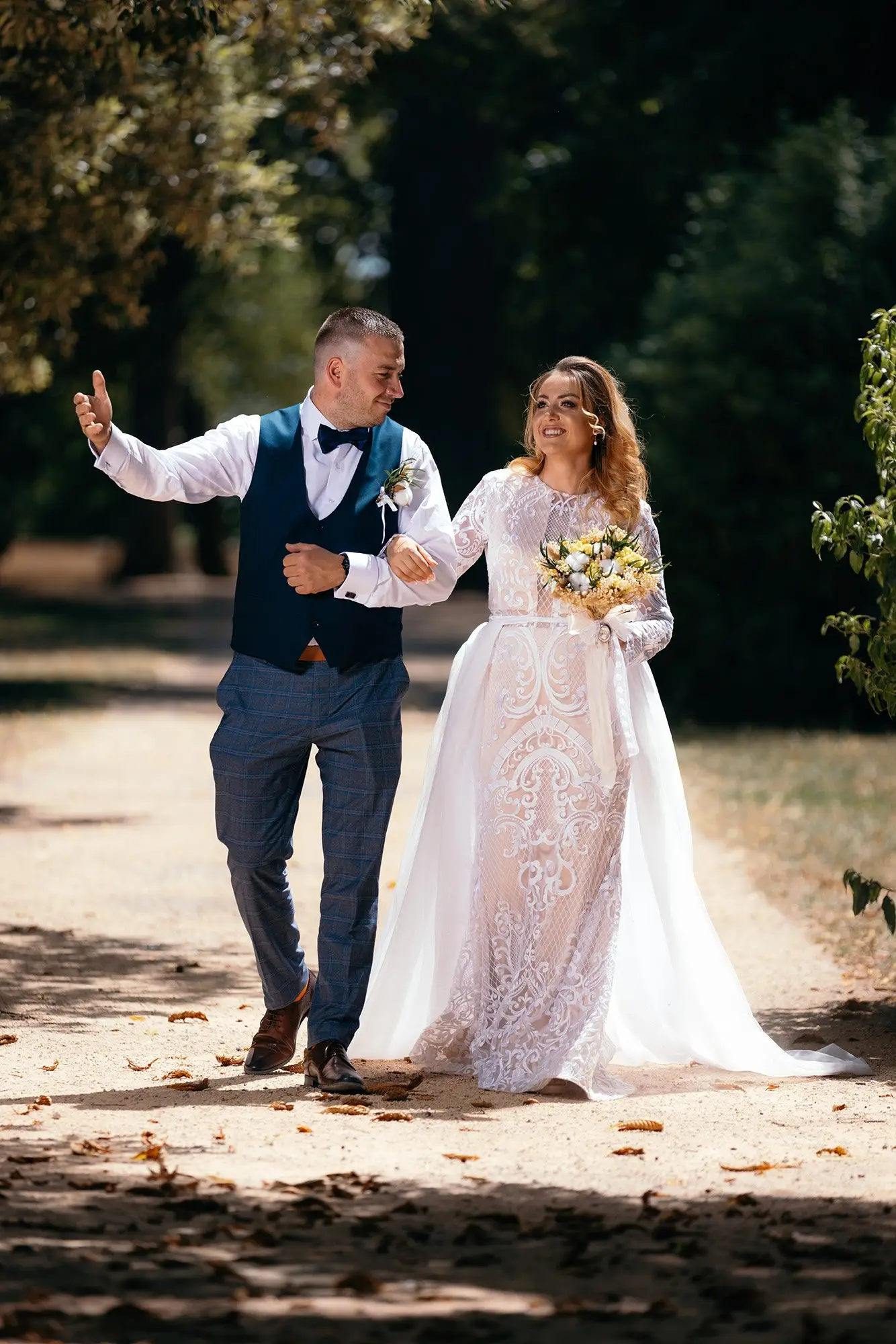 Les mariés marchent bras dessus bras dessous dans une allée ombragée — reportage de mariage