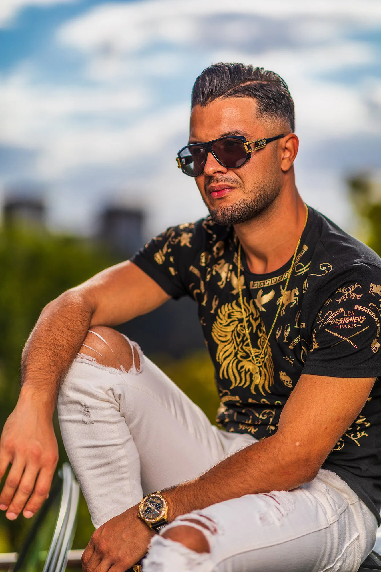 Portrait lifestyle d’Alaa en lunettes de soleil, assis en extérieur