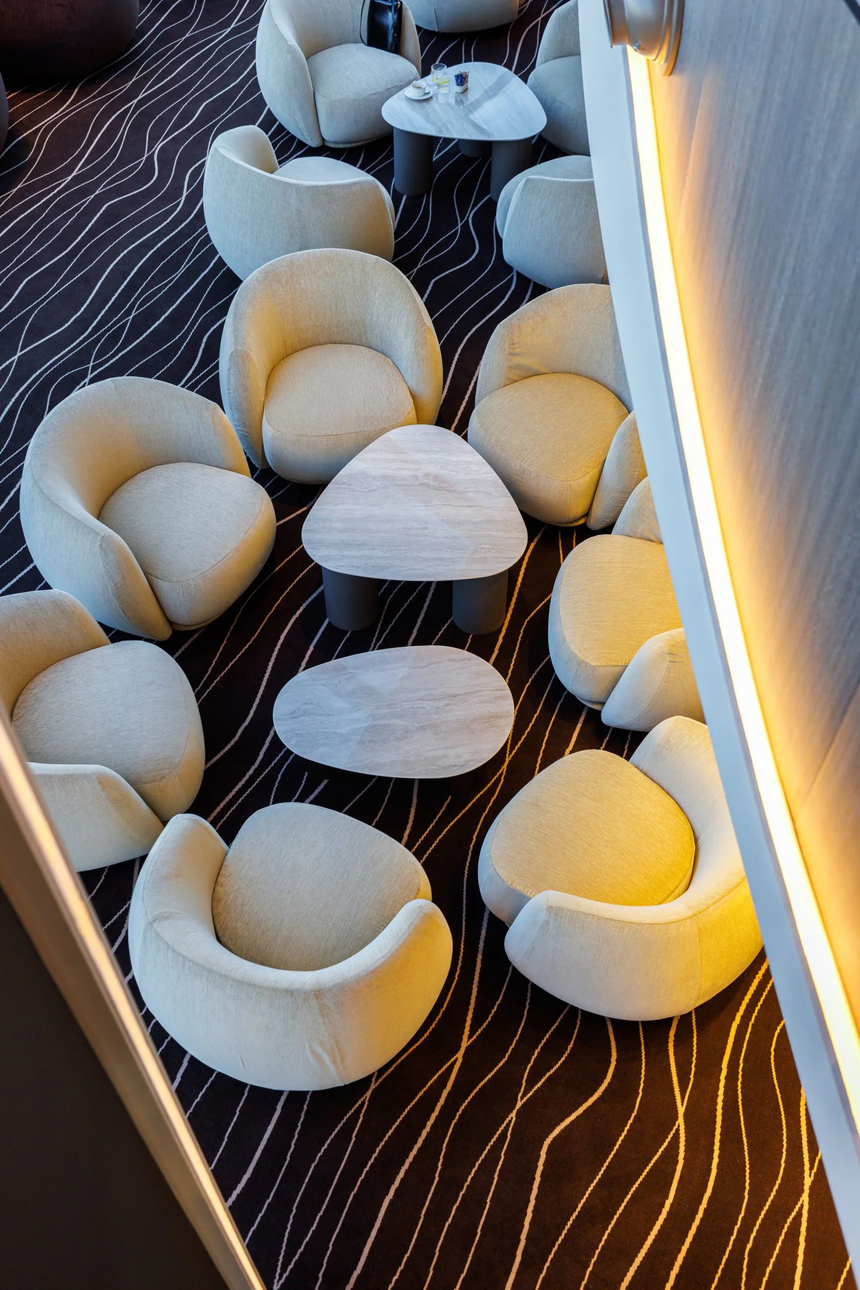 Salon avec plusieurs fauteuils jaunes et tables en marbre, vue de dessus.