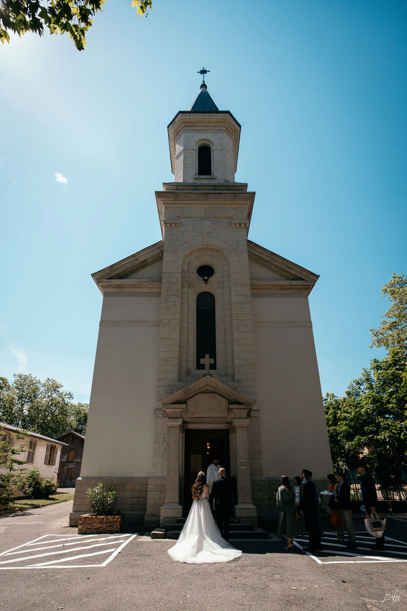 Lucia et Victor devant une chapelle blanche sous le ciel bleu