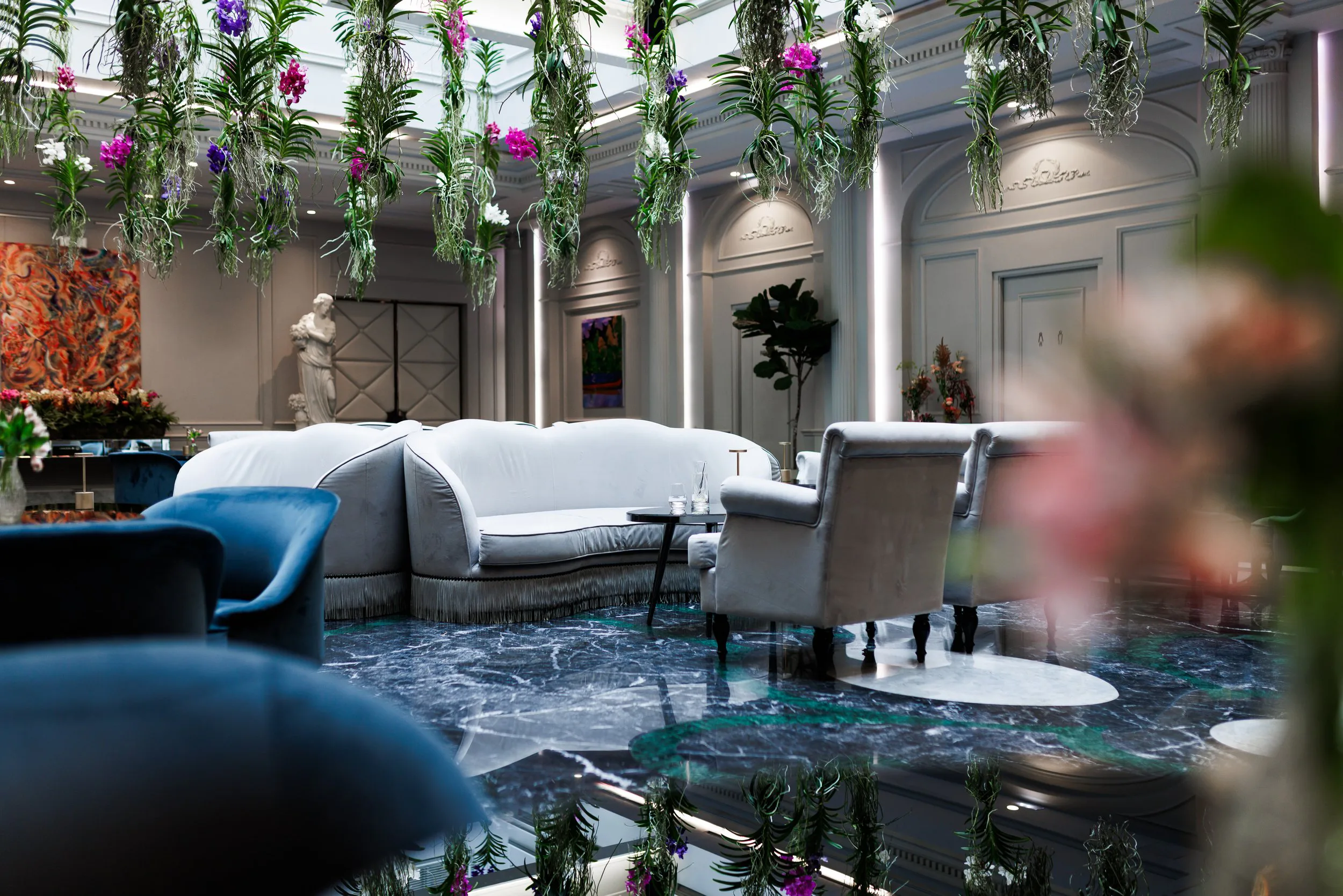 Intérieur élégant d'un salon avec des meubles en velours, des plantes suspendues et des œuvres d'art sur les murs.