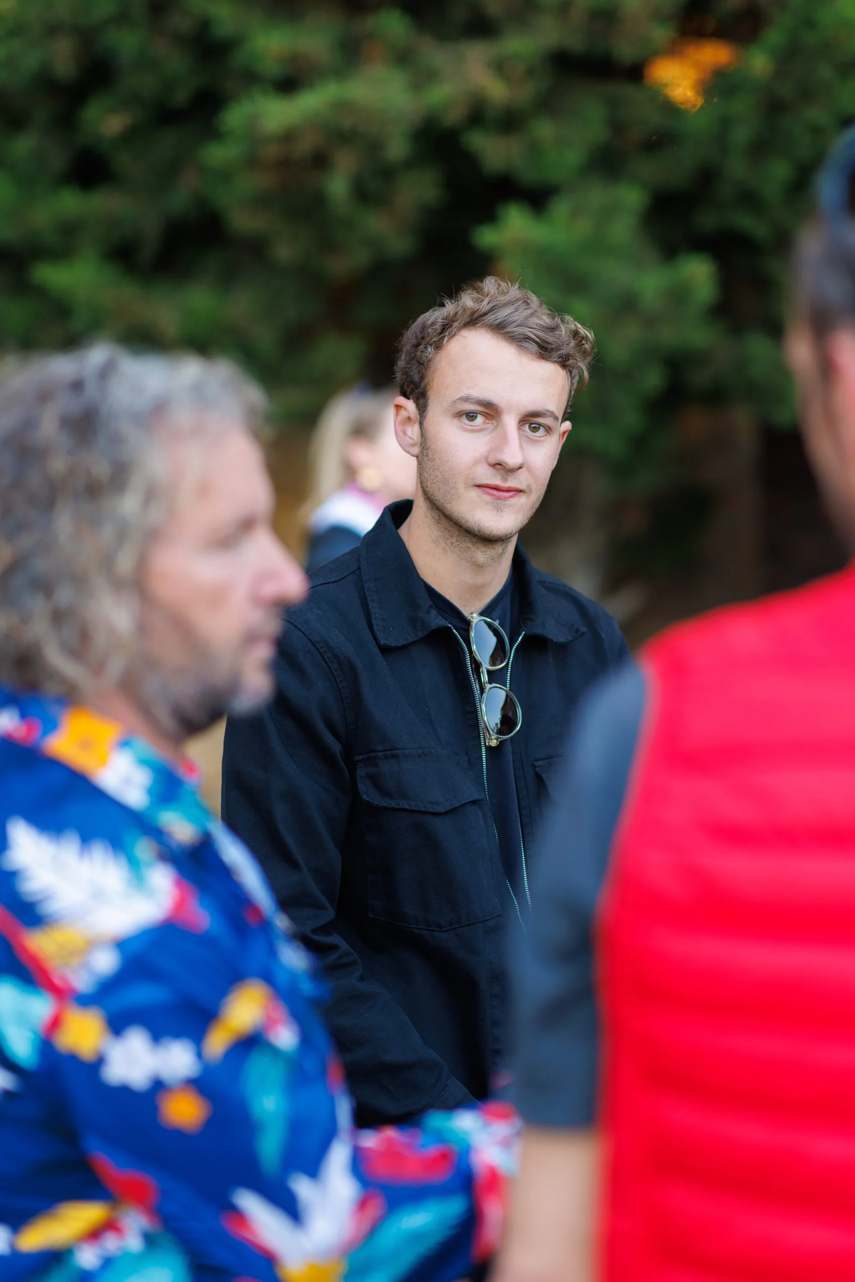 Groupe de personnes en discussion en plein air, arrière-plan de nature avec des arbres.
