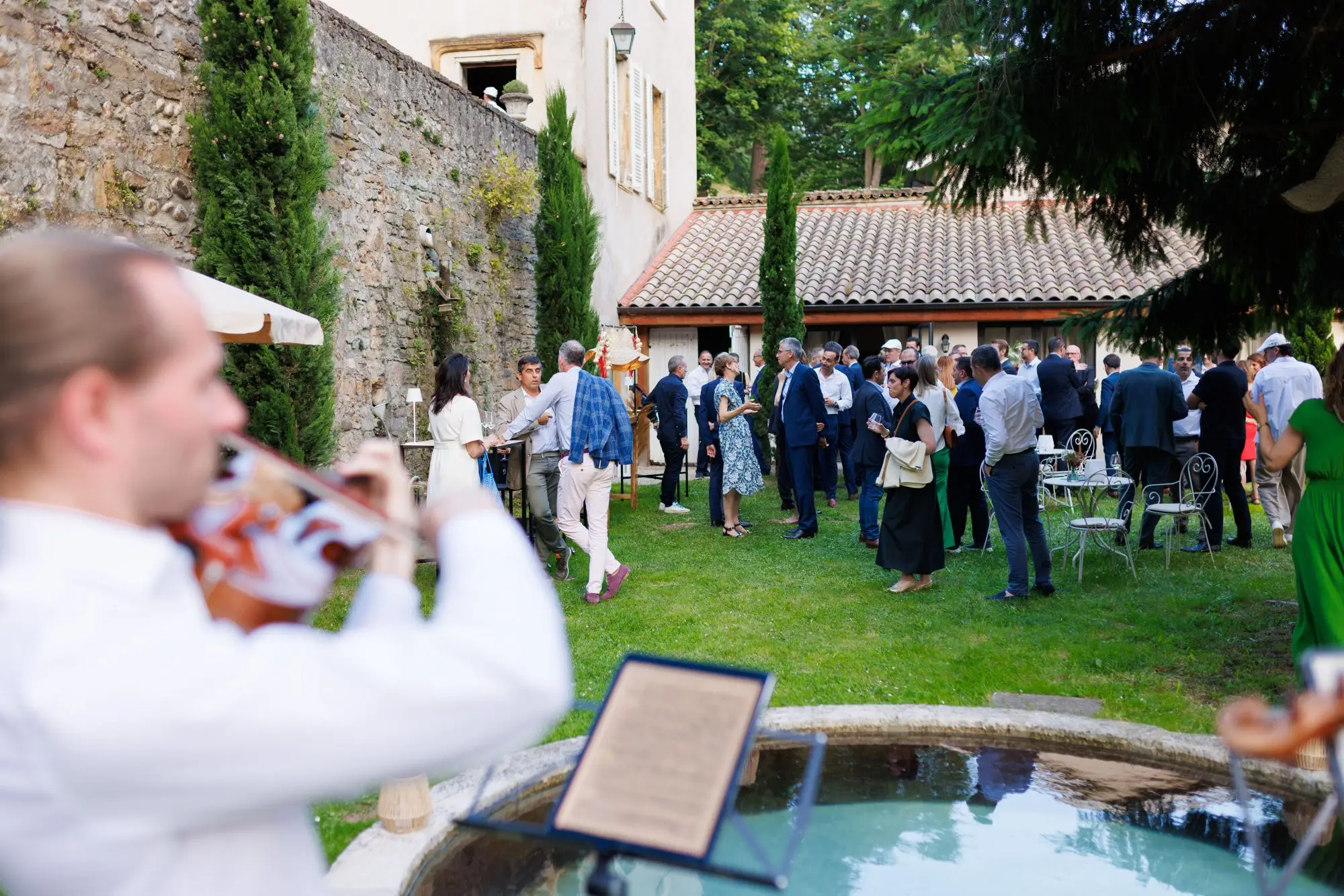Cocktail d’entreprise dans un jardin, avec un violoniste au premier plan — photographe événementiel à Lyon