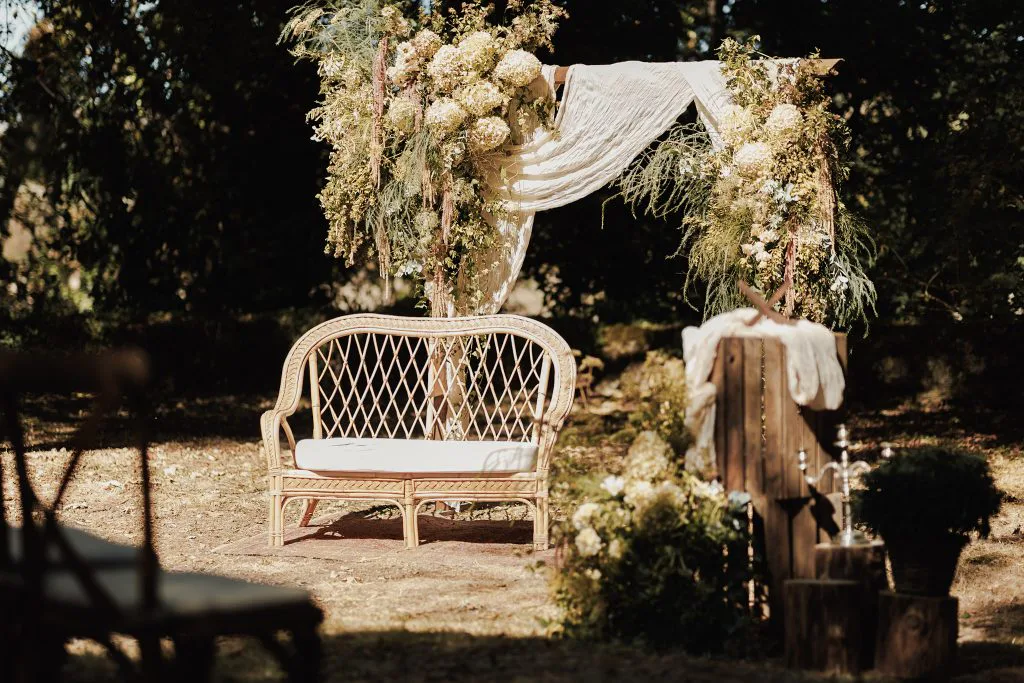 Arche fleurie et banquette en rotin pour la cérémonie laïque dans les jardins du Château de Courbeville