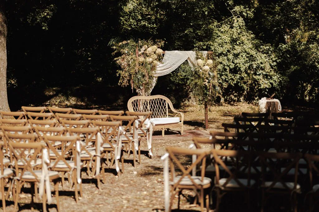 Chaises en bois alignées sous les arbres pour la cérémonie laïque