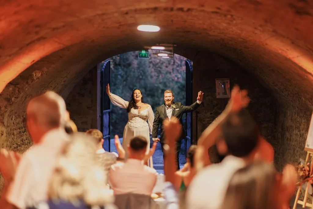 Entrée des mariés sous la Grande Voûte, bras levés, ovation des invités