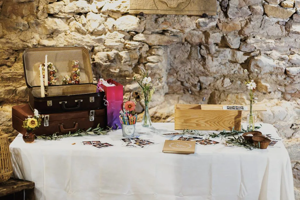 Livre d’or et valise vintage sur une table de pierre décorée de fleurs