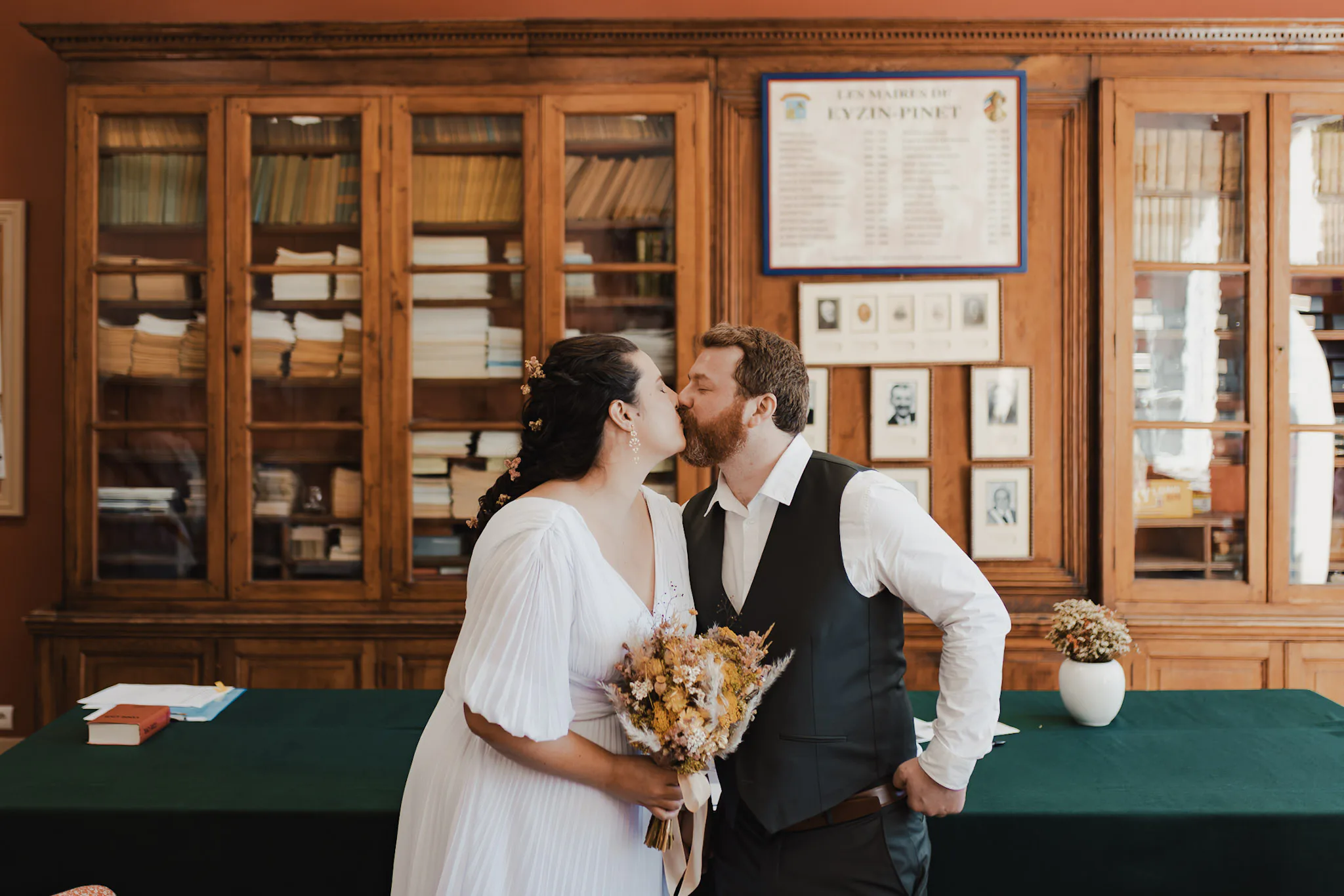 Camille et Jason s’embrassent dans la salle des mariages de la mairie, bouquet de fleurs séchées à la main