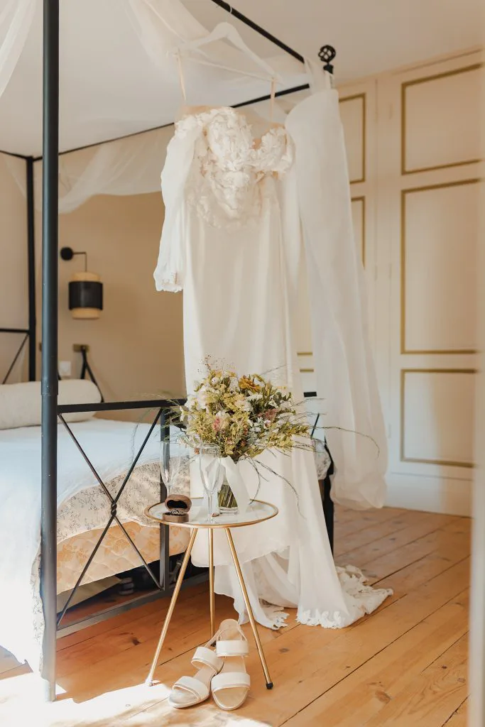 La robe de mariée de Camille suspendue dans une chambre du château, avec le bouquet