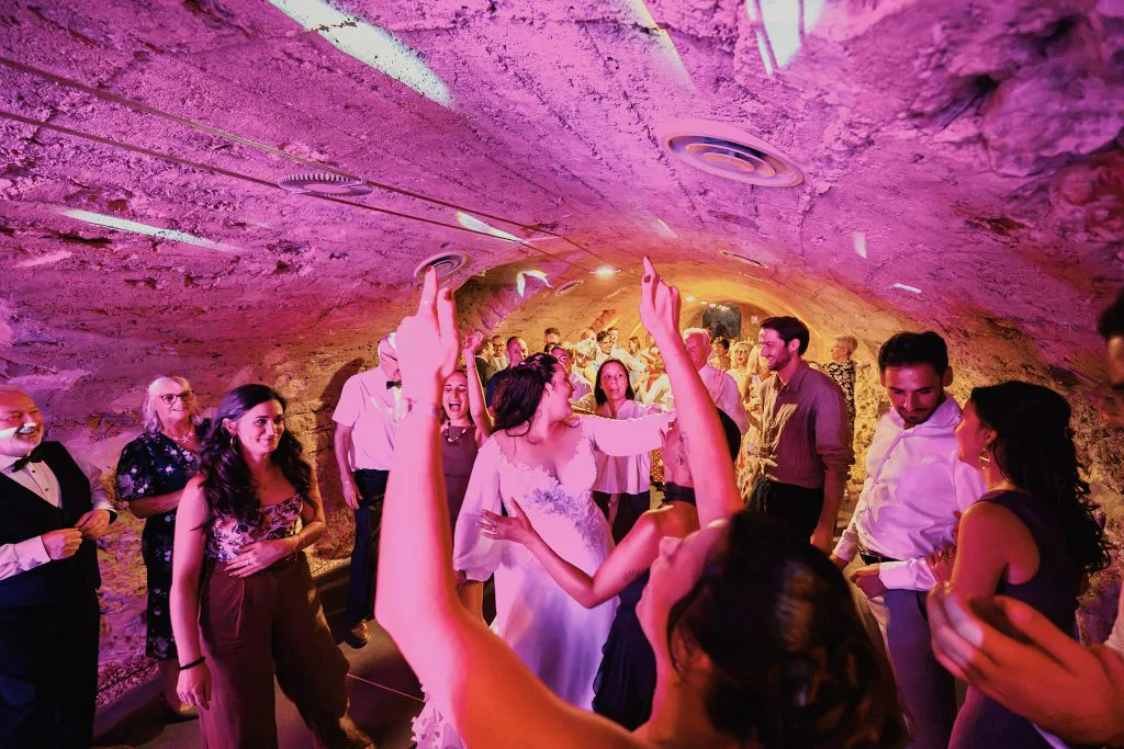 Soirée dansante sous la voûte en pierre, lumières roses et invités déchaînés
