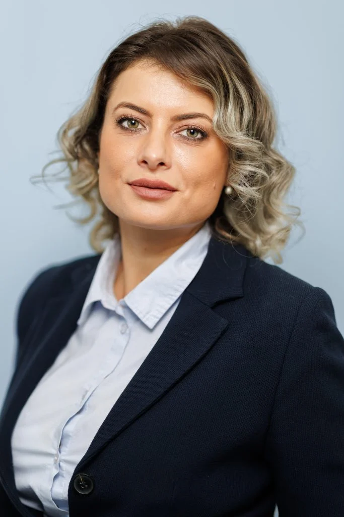 Portrait professionnel d’une femme en tailleur bleu marine sur fond bleu clair, à Lyon